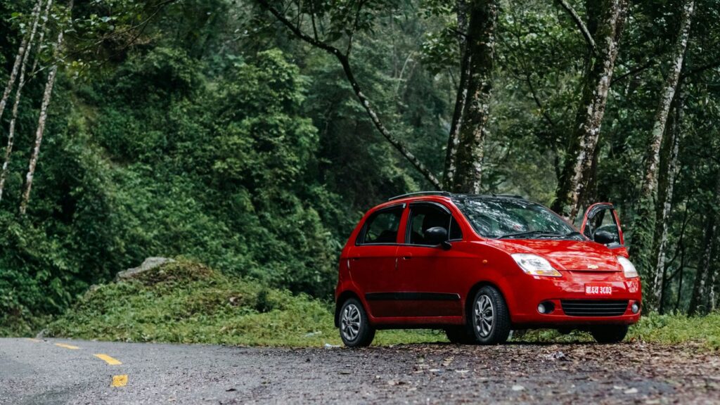 a small red car parked on the side of a road