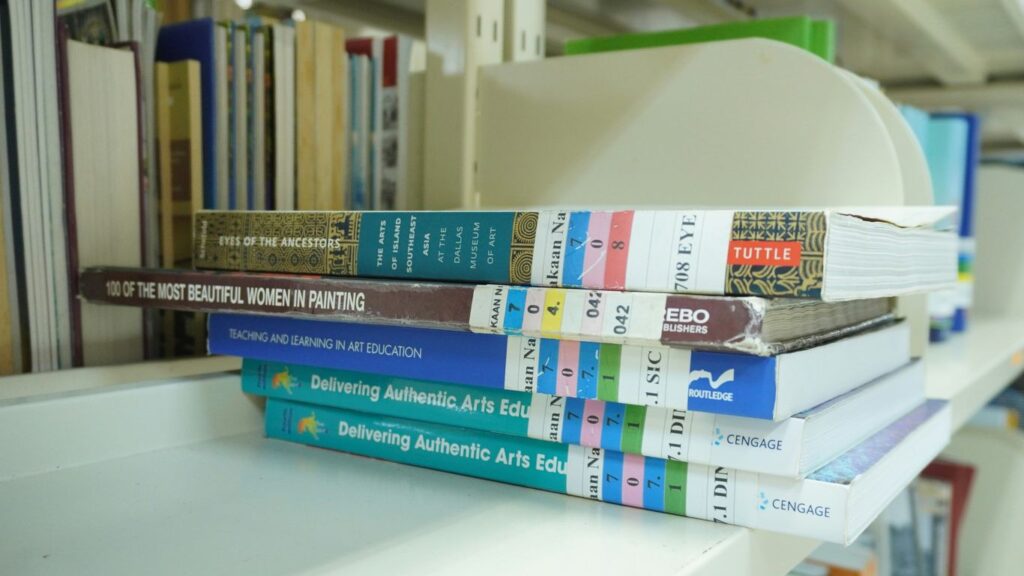 A stack of books sitting on top of a white shelf