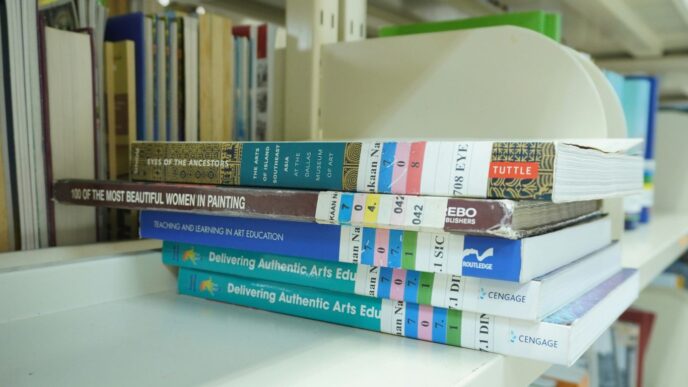 A stack of books sitting on top of a white shelf