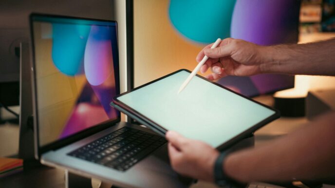 A person holding a pen and writing on a laptop