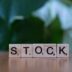 A wooden block spelling the word stock on a table
