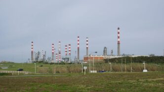 An industrial plant with chimneys and infrastructure is visible.