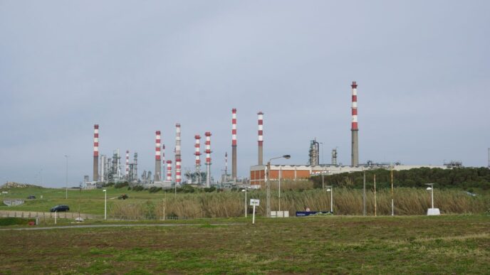 An industrial plant with chimneys and infrastructure is visible.
