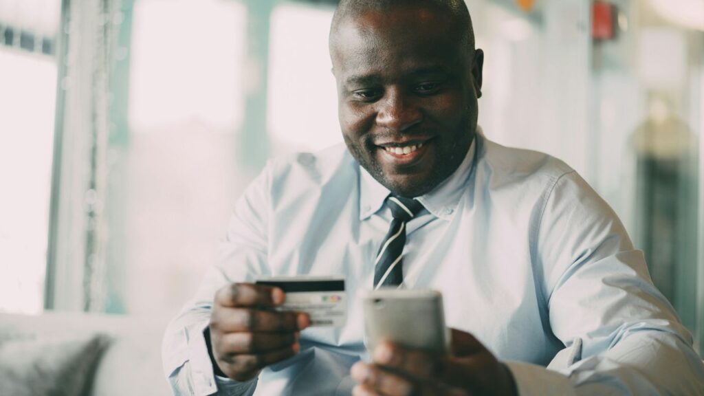 Man smiling while holding credit card and phone