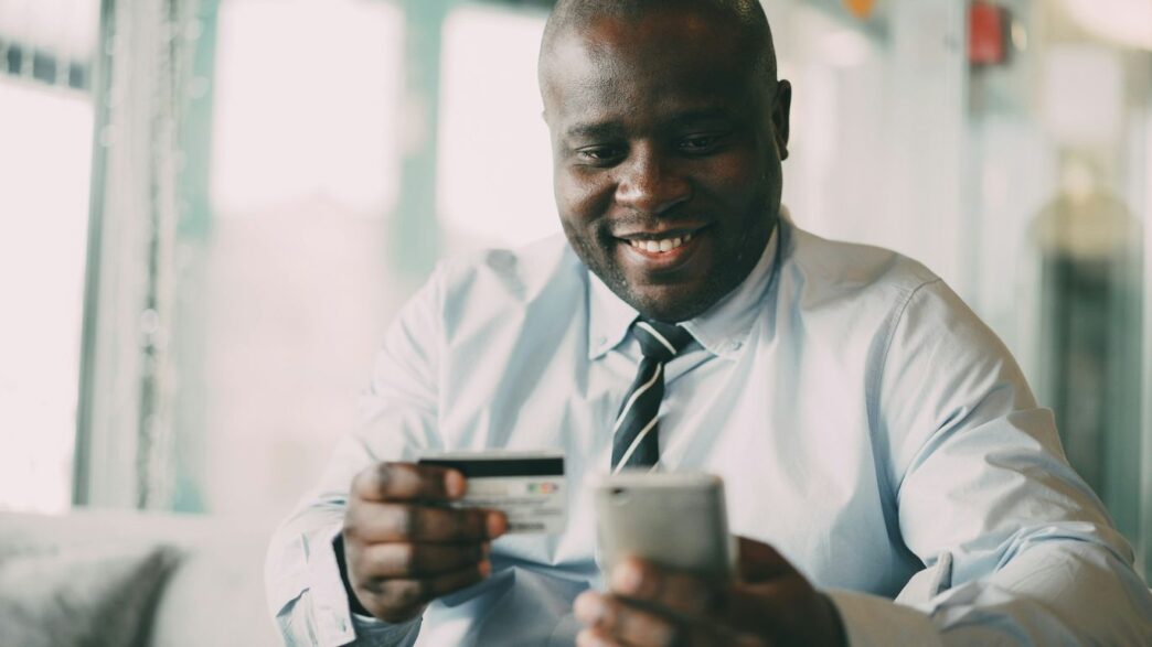 Man smiling while holding credit card and phone