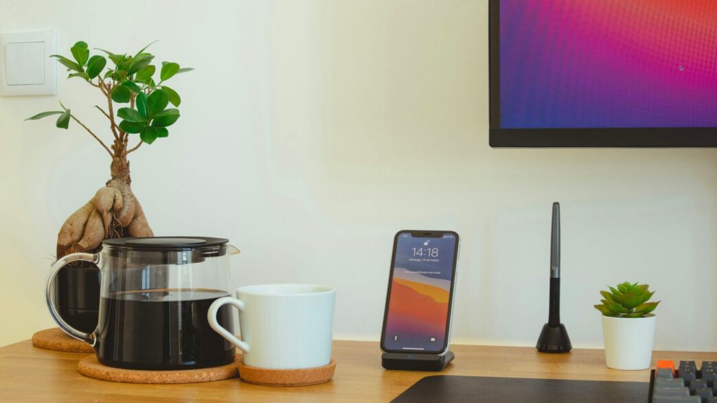 black iphone 7 beside white ceramic mug on brown wooden table