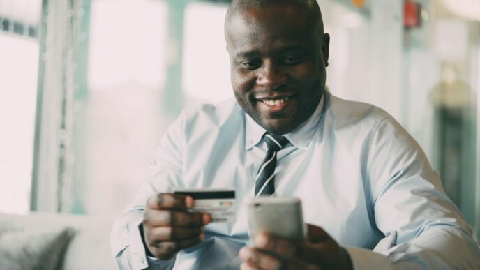 Man smiling while holding credit card and phone