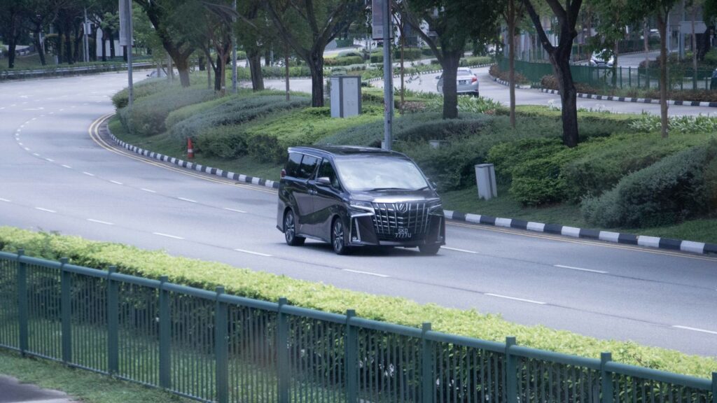A car driving down a street next to a fence