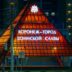 Illuminated pyramid monument at night with russian text