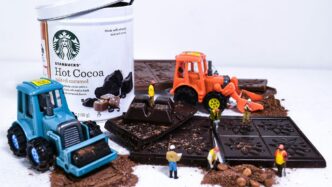 a container of hot cocoa next to a couple of toy tractors