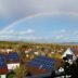 Rainbow over a suburban neighborhood with solar panels.