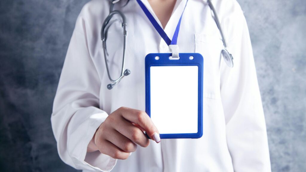 person in white and blue medical scrub holding blue and white card