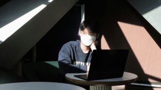 a man sitting at a table using a laptop computer