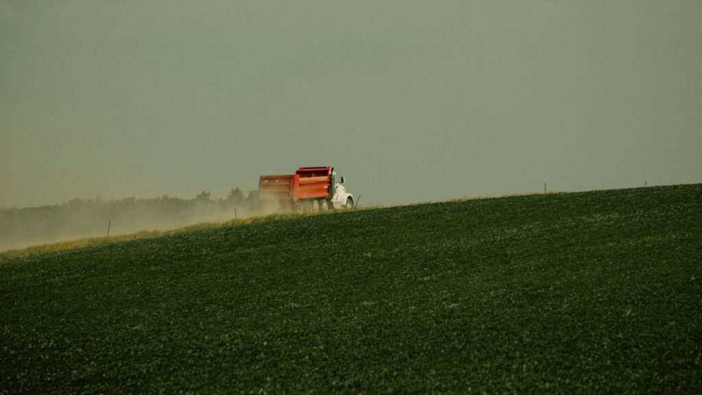 a red truck driving across a lush green field