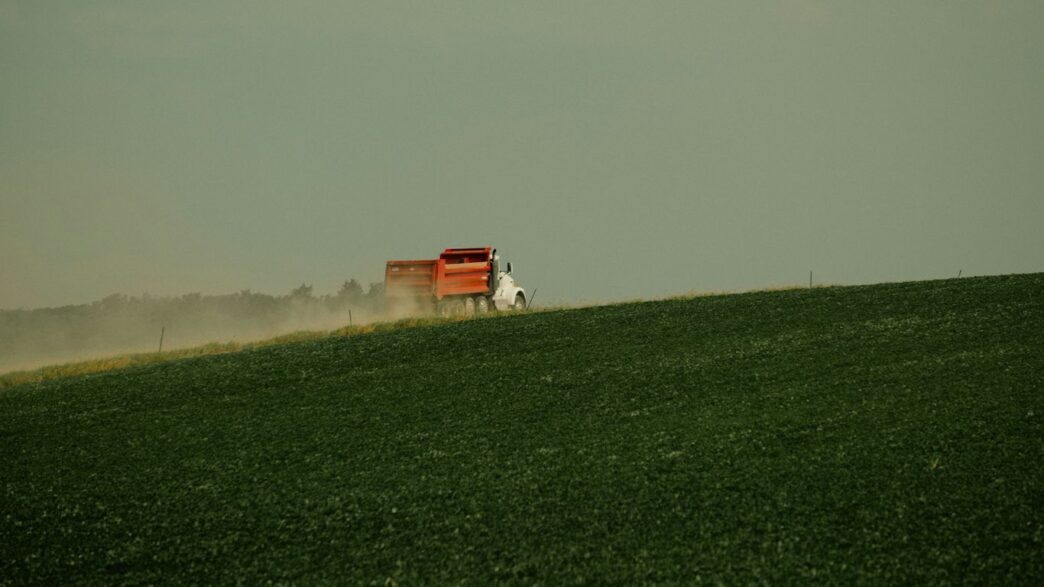 a red truck driving across a lush green field