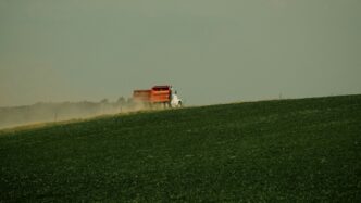 a red truck driving across a lush green field