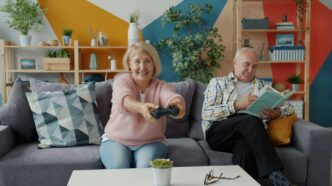 Elderly couple playing video games and reading.