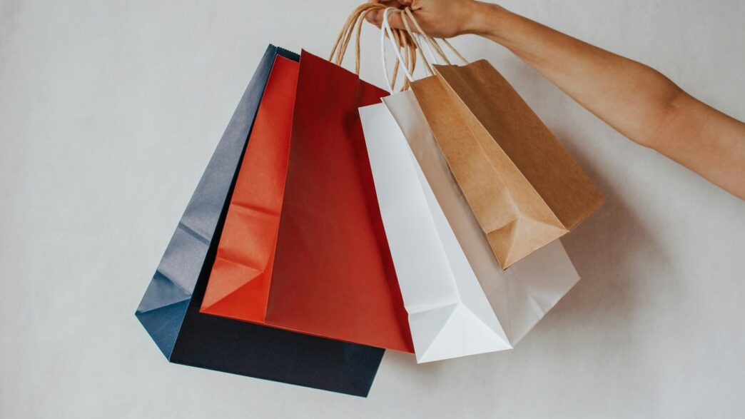 Hand holding colorful shopping bags against a white background