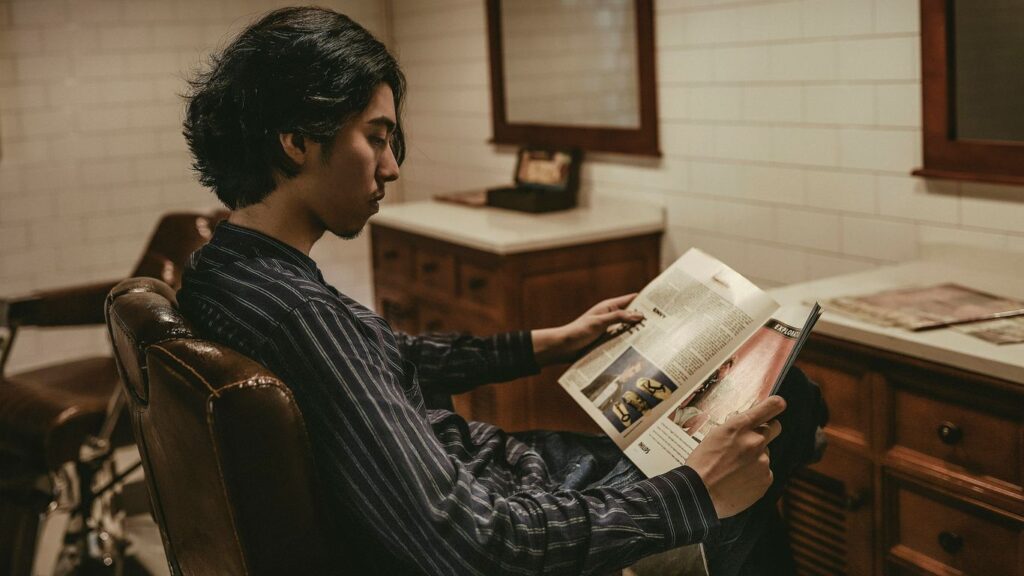 boy reading book while sitting on sofa chair