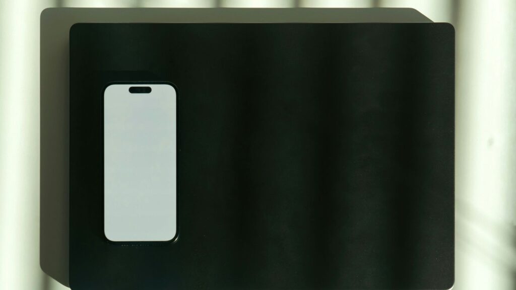 A white smartphone is placed on a black surface.