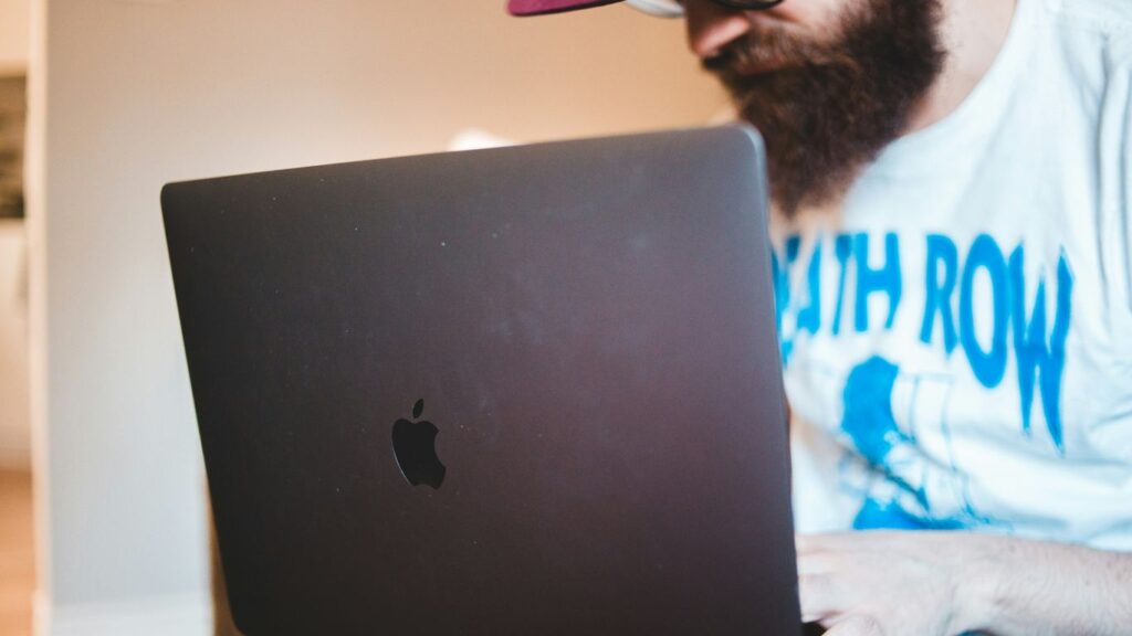 man in white shirt using black macbook