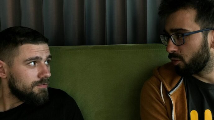 a couple of men sitting on top of a green couch