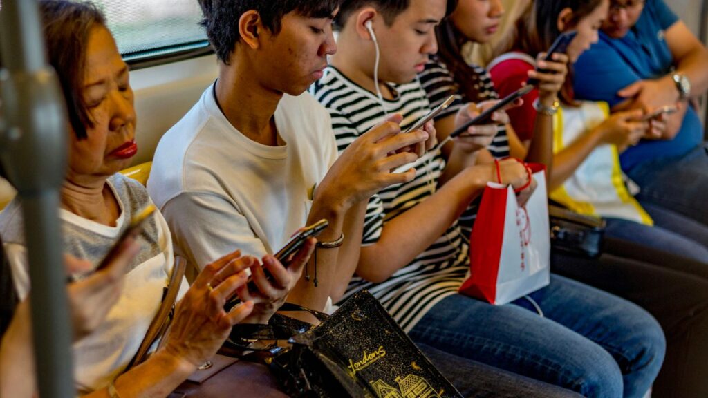 people using smartphones while sitting inside train