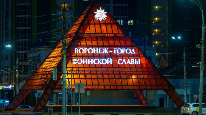 Illuminated pyramid monument at night with russian text