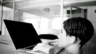 a young boy sitting in front of a laptop computer
