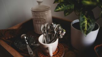 silverware in white ceramic mug beside coffee jar