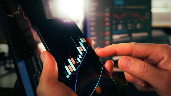 Hands holding smartphone showing stock market data