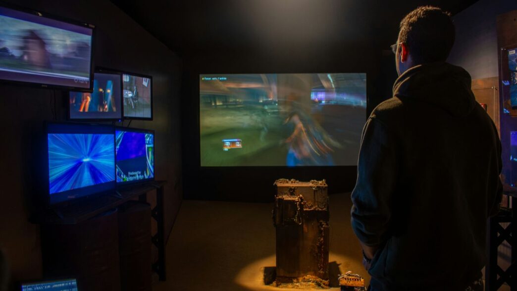 A man watches video games on multiple screens.