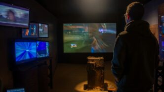 A man watches video games on multiple screens.