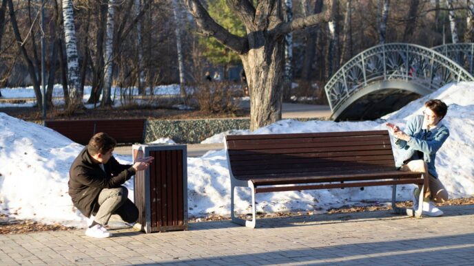 Two people interacting with a trash can and bench