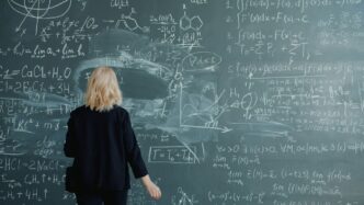 Woman looking at a blackboard with complex math equations.