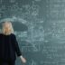 Woman looking at a blackboard with complex math equations.