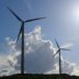 a group of windmills on a hill under a blue sky