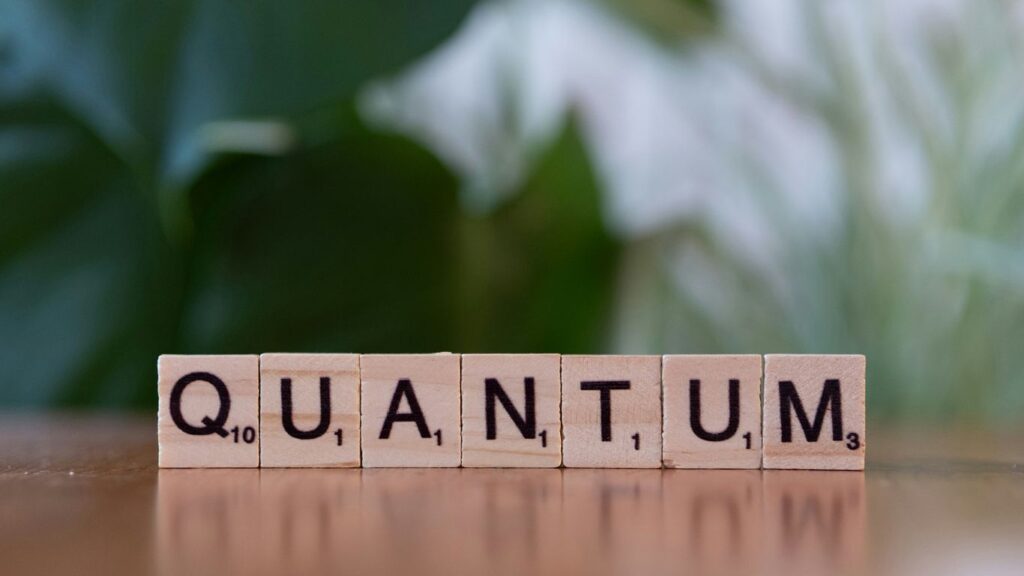 A wooden block spelling the word quanntum on a table
