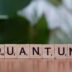 A wooden block spelling the word quanntum on a table