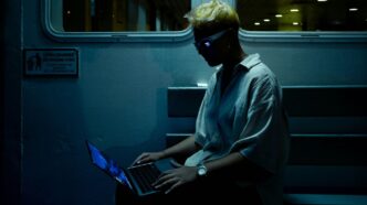A man sitting on a train using a laptop computer