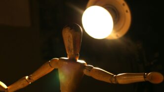 a wooden mannequin standing in front of a light