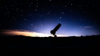 a telescope sitting on top of a hill under a night sky