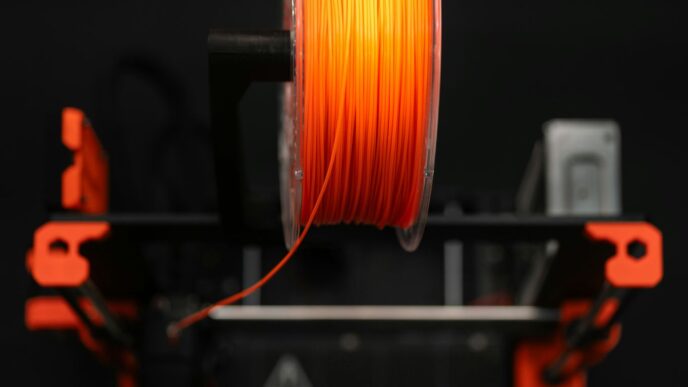 A spool of orange colored pla on a machine