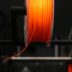 A spool of orange colored pla on a machine