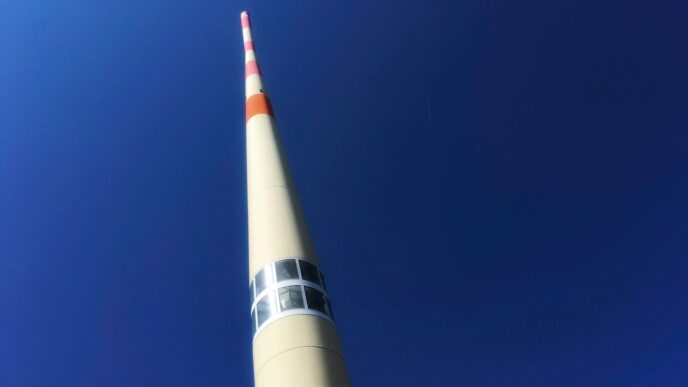 a tall white tower with a red and white stripe on it