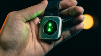 Hand holding smartwatch with glowing green sensor