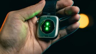 Hand holding smartwatch with glowing green sensor