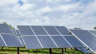 Solar panels in a field under a cloudy sky
