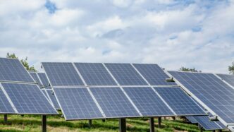 Solar panels in a field under a cloudy sky