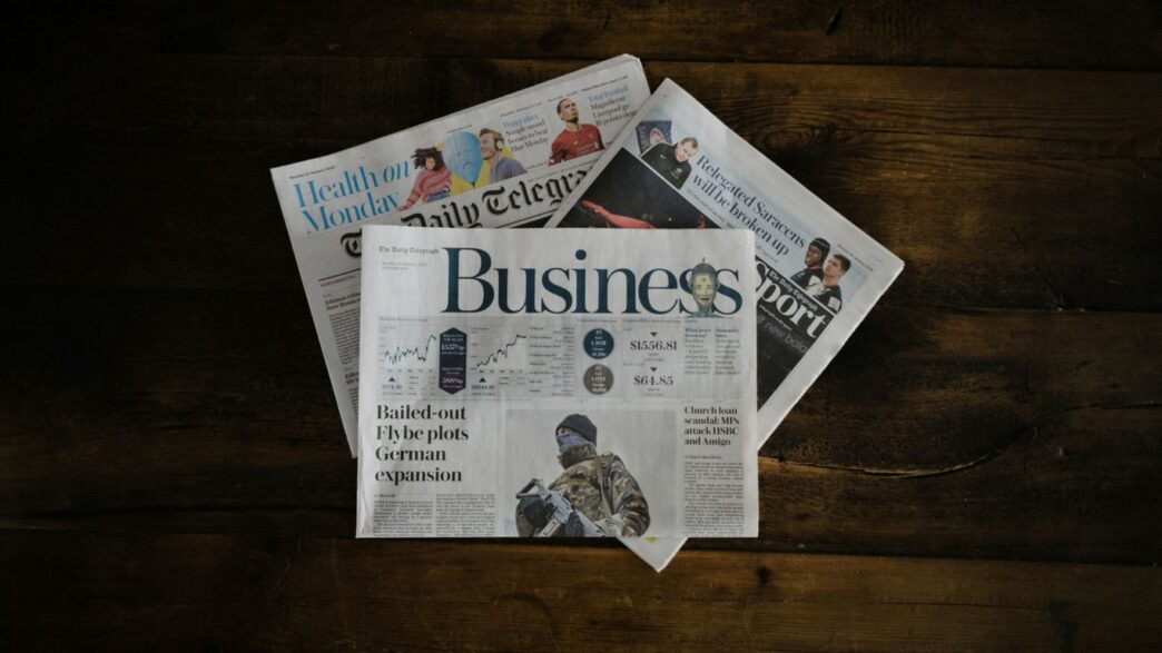 a stack of newspapers sitting on top of a wooden table